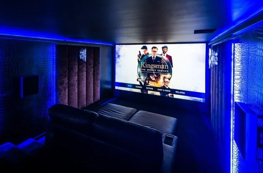 Garden room cinema with a large screen, blue mood lighting and seating